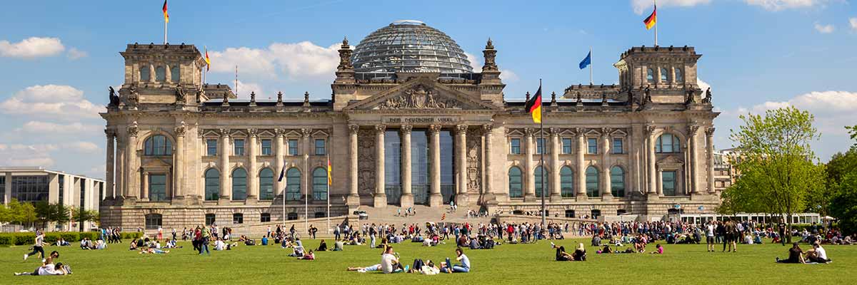 Deutscher Bundestag, davor Sitzen viele Menschen auf der Wiese in friedlicher Stimmung